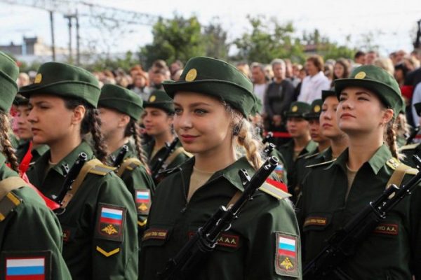 На фотографии стояла девушка в военной форме в солдатских сапогах в гимнастерке и юбке